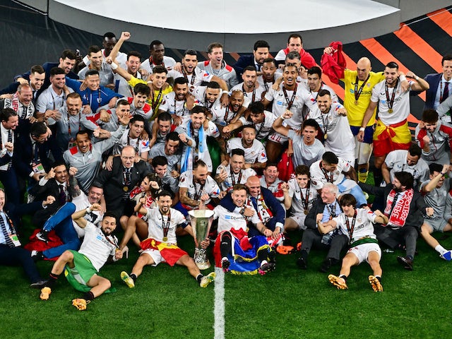 لاعبو إشبيلية يقفون لالتقاط صورة مع الكأس بعد فوزهم بالدوري الأوروبي في 31 مايو 2023
